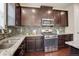 Close up on a kitchen with stainless steel appliances, granite countertops, mosaic tile backsplash, and dark wood cabinets at 13351 Olive Way, Thornton, CO 80602