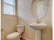 Small, stylish powder room with a pedestal sink, toilet, and window at 13351 Olive Way, Thornton, CO 80602