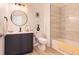 Updated bathroom with dark vanity, tile surround, and round mirror at 9557 Pearl Cir # 204, Parker, CO 80134
