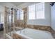 Luxurious bathroom featuring a separate shower and soaking tub with travertine tile surround and window at 25525 E 1St Ave, Aurora, CO 80018
