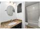 Bathroom featuring vanity with granite countertop, round mirror, and shower with marble tile at 8873 Yukon St, Broomfield, CO 80021