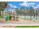 A playground featuring green slides and mature trees and bushes and a basketball court in background at 8873 Yukon St, Broomfield, CO 80021