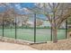 Tennis court with a green surface and black fence, complemented by lush trees and gravel landscaping at 8873 Yukon St, Broomfield, CO 80021