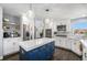 Modern kitchen features stainless appliances, ample cabinets, a blue island and hardwood floors at 10144 Madison St, Thornton, CO 80229