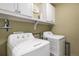 A tidy laundry room featuring a side-by-side washer and dryer, overhead cabinets, and a shelf at 10144 Madison St, Thornton, CO 80229