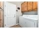 Functional laundry room with wooden cabinets, washer, dryer, and a door to the outside at 787 Kendall Ct, Lakewood, CO 80214