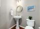 Stylish powder room with pedestal sink, round mirror, and modern lighting at 787 Kendall Ct, Lakewood, CO 80214