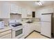 Galley kitchen featuring white appliances, ample cabinet space, and a double basin sink at 625 S Alton Way # 3D, Denver, CO 80247