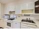 Galley kitchen featuring white appliances, ample cabinet space, and a double basin sink at 625 S Alton Way # 3D, Denver, CO 80247