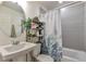 This full bathroom features a stylish sink, a decorative shower curtain, and neutral-colored tile at 3963 N Quatar Ct, Aurora, CO 80019