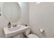 This powder room features a sleek pedestal sink, a round mirror, and a convenient toilet paper holder at 3963 N Quatar Ct, Aurora, CO 80019