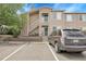 Tan apartment building with a car in the parking lot, stairway to the second floor, and a tree at 8475 Pebble Creek Way # 204, Highlands Ranch, CO 80126