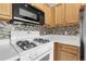 Well-lit kitchen featuring a white gas range, microwave and stylish mosaic tile backsplash at 8475 Pebble Creek Way # 204, Highlands Ranch, CO 80126