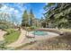 Community pool with a cover, surrounded by trees, a grassy area, and a bridge at 8475 Pebble Creek Way # 204, Highlands Ranch, CO 80126
