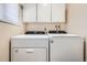 Bright laundry room featuring white Whirlpool washer and dryer, and white cabinetry for convenient storage at 2111 W 80Th Ave, Denver, CO 80221