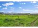 Expansive open field with lush green grass, distant mountains, and a clear blue sky with clouds at 14735 W Ellsworth Ave, Golden, CO 80401