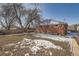 Backyard with a mix of grass and snow leading to a brick home at 6032 Estes St, Arvada, CO 80004