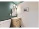 Stylish bathroom with a wood vanity, gold fixtures, and green accent wall at 6876 Quay Ct, Arvada, CO 80003