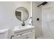 Bathroom featuring a white vanity, round mirror, and tiled shower at 6876 Quay Ct, Arvada, CO 80003