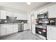 Contemporary kitchen with white cabinets, stainless steel appliances, and stylish gray backsplash at 932 Quentin St, Aurora, CO 80011