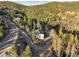 Aerial view showcases a white home nestled in mountains surrounded by lush greenery and winding roads at 9790 City View Dr, Morrison, CO 80465