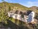 Charming single-story home with a white exterior, surrounded by lush greenery and mature trees at 9790 City View Dr, Morrison, CO 80465