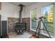 Cozy living space featuring a wood-burning stove, stone accent wall, and a large window with a telescope at 9790 City View Dr, Morrison, CO 80465