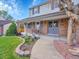 Inviting two-story home featuring a brick facade, covered porch, and mature landscaping at 7405 S Jackson Ct, Centennial, CO 80122