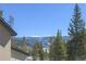 Scenic mountain view with snow-capped peaks framed by lush green trees; partial house visible at 2035 Highlands Dr, Breckenridge, CO 80424