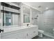 Modern bathroom with white vanity, black fixtures, large mirror, and glass shower at 3184 S Heather Gardens Way # 406, Aurora, CO 80014