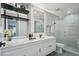Elegant bathroom with a marble wall, double vanity, framed mirror, and a glass-enclosed shower at 3184 S Heather Gardens Way # 406, Aurora, CO 80014