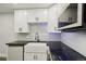 Modern kitchen with white cabinetry, black countertops, stainless steel appliances and subway backsplash at 3184 S Heather Gardens Way # 406, Aurora, CO 80014