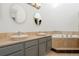 Bathroom featuring a double sink vanity with matching round mirrors and a soaking tub at 9400 E Iliff Ave # 37, Denver, CO 80231