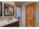 Bathroom featuring a single sink vanity with granite countertop, one mirror and solid wood door at 45 Oak Way, Evergreen, CO 80439