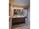 Bathroom featuring a double sink vanity with granite countertop, two mirrors and views into the bedroom at 45 Oak Way, Evergreen, CO 80439