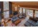 Spacious living room with stone fireplace, wood ceiling, ample natural light, and mountain views at 45 Oak Way, Evergreen, CO 80439