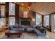 A comfortable living room featuring a stone fireplace, wood ceiling, and large windows with natural light at 45 Oak Way, Evergreen, CO 80439