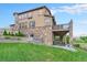Beautiful two-story home with a stone exterior and a large backyard featuring a well-maintained lawn at 10705 Pinewalk Way, Highlands Ranch, CO 80130