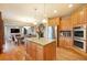 Open kitchen with an island, stainless steel appliances, and hardwood floors flows into the dining and living area at 10705 Pinewalk Way, Highlands Ranch, CO 80130