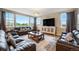 Spacious living room with large windows, comfortable sofas, and a modern entertainment center at 10705 Pinewalk Way, Highlands Ranch, CO 80130