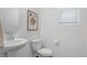 Bright half bathroom with a pedestal sink, toilet, and framed picture at 17548 Bluetrail Ave, Parker, CO 80134