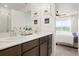 Bright bathroom with double sinks and view into bedroom with ceiling fan and large window at 17548 Bluetrail Ave, Parker, CO 80134