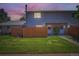 Charming townhome featuring a well-maintained lawn, stone accents, and a private wooden fence at dusk at 1211 W 112Th Ave # B, Denver, CO 80234