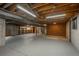 Large basement with exposed ceiling, brick accent wall and concrete foundation at 5361 Nassau Cir, Cherry Hills Village, CO 80113