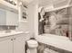 Well-lit bathroom featuring a tub, gray tile surround, vanity with sink, and mirrored cabinet, offering a clean functional space at 1956 Cathay St, Aurora, CO 80011