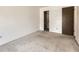 An empty bedroom with neutral carpet and walls, closet with built in shelves, and a brown door at 1956 Cathay St, Aurora, CO 80011