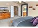 Comfortable primary suite with a view into the ensuite bathroom and a wall-mounted TV above a wooden dresser and carpet at 1168 Coneflower Way, Brighton, CO 80601