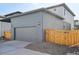 Gray detached garage with a large door and exterior lighting, next to house at 21021 E 63Rd Dr, Aurora, CO 80019