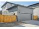 Gray detached garage with a large door and wooden fence at 21021 E 63Rd Dr, Aurora, CO 80019