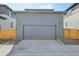 A detached two car garage with gray siding and featuring a concrete driveway and stone landscaping at 21021 E 63Rd Dr, Aurora, CO 80019